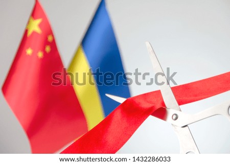 Ribbon cutting ceremony. Scissors cut red ribbon. 
China and Ukraine flag bluered on the background. start of a partnership concept