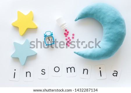 Insomnia concept with moon, stars, alarm clock and pills on white background top view