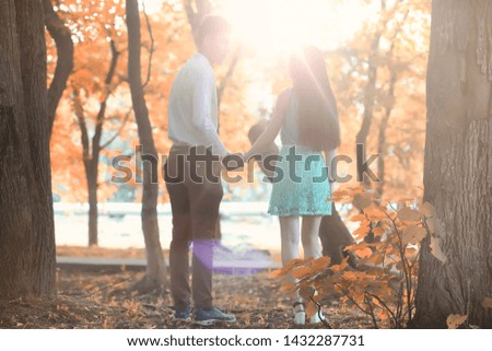 Young couple on a walk in autumn beautiful park at sunset
