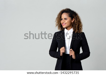 Cheerful African American business woman in black suit with curly hair looking away isolated against gray background Royalty-Free Stock Photo #1432295735