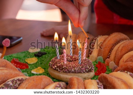 A close up view of five pink and blue candels being lite on a doughnut cake