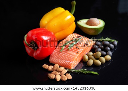     A slice of raw salmon fillet with a sprig of rosemary, red and yellow sweet peppers, almond nuts, green and black olives and slice                             