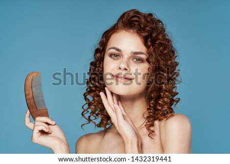 Blue background wooden comb bare shoulders beautiful face curly woman cropped look