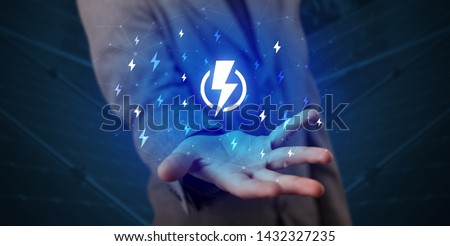 Hand in suit holding lightning bolt on his hand, green environment concept