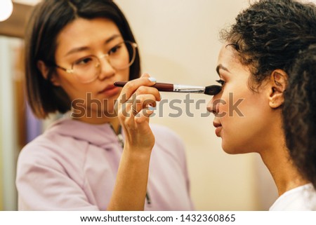 Close up of make up artist hand shading under the eyes of a model