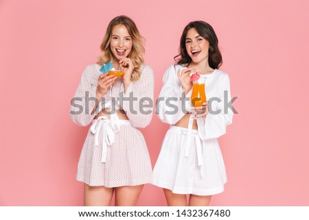 Image of excited happy young pretty women friends posing isolated over pink wall background drinking cocktails.