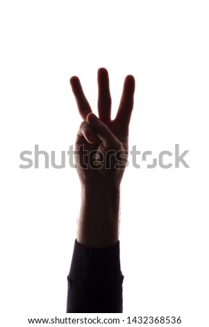 The hand of a young man with his fingers apart, number the three - silhouette, concept abstraction