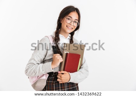 Photo closeup of happy teenage girl wearing eyeglasses stressing and grabbing her head while holding studying books isolated over white background