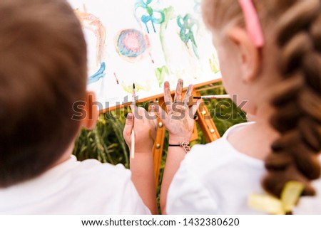 Kids painting outside on easel stand 