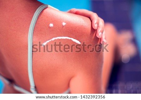Woman with sun protection cream on her shoulder in the shape of sad smile. Summer, healthcare and vacation concept
