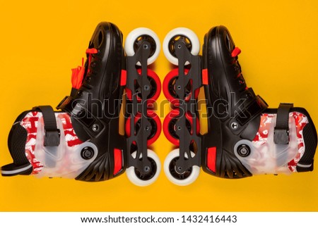 A pair of red roller skates on yellow background , shot from above.