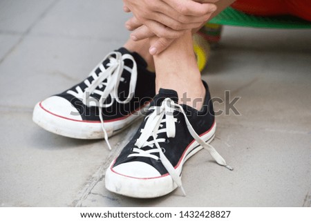 Close up image of boy in sneakers sitting on the skateboard.
