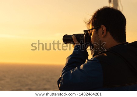 man photographing the sunset at sea