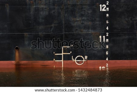 Plimsoll at the side of a bulk carrier in port. When a ship is being loaded, the water level must not exceed the line. This line is also called Load Line or Plimsoll Line. Royalty-Free Stock Photo #1432484873