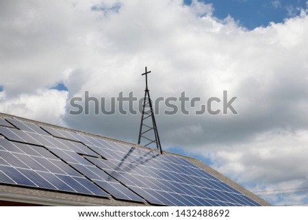 A church using renewable energy, with solar panels mixed in with a sign of the cross 