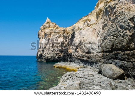 A cliff face along the Maltese coastline, showing features of sea erosion and cliff recession. Wave cut platform at sea level and cracks and boulders. Royalty-Free Stock Photo #1432498490