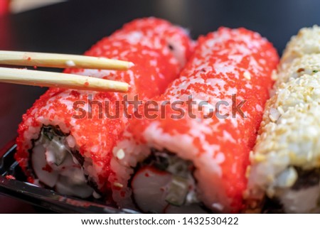 Wooden sticks lie on red sushi on a black background close-up. The concept of Japanese cuisine.