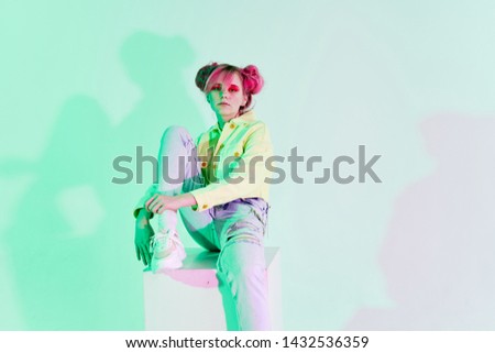 woman with pink hair sits on a cube on a green background fashion