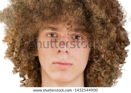 portrait of a young curly European man with long curly hair and a defiant gaze looks into the frame close-up. very lush male hair from a guy. a lock of passion. isolated on white background.