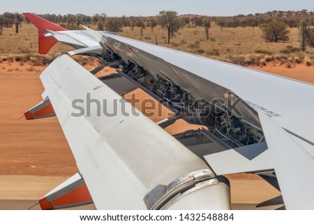 Airplane activates ground spoilers as it lands at the Ayers Rock airport in Australia Royalty-Free Stock Photo #1432548884