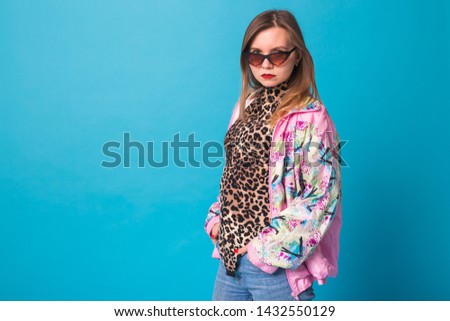 Vintage fashion look concept - pretty young woman wearing a retro pink jacket and leopard body on blue background with copy space