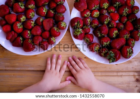 
baby hands and strawberries in a plate