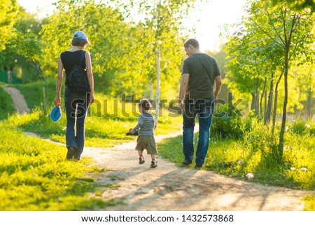 Portrait of Young Caucasian Family of Three Together Outdoors. Having a Stroll. Horizontal Image