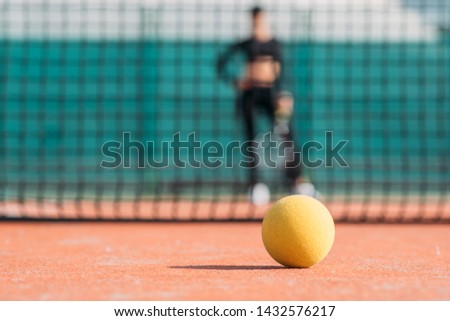 tennis ball close up on tennis court with girl on background