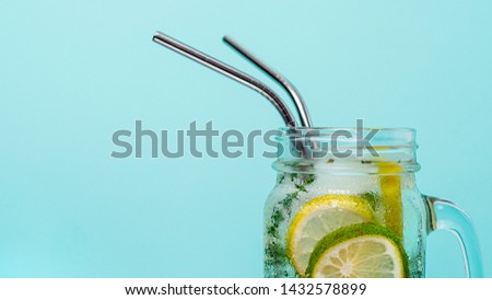 Cold drink in mason jar with metal straw on blue background. Lemonade or detox water with lime and thyme in glass jar with copy space for text or design. Recyclable straws, zero waste concept. Banner. Royalty-Free Stock Photo #1432578899