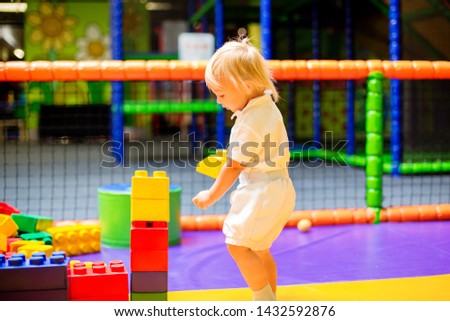 Little toddler child, boy playing in children playground indoors, kid plays in kindergarden playground