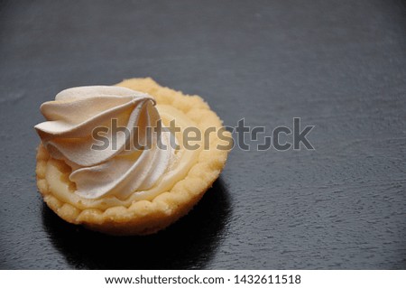 A small lemon meringue tart on a black background