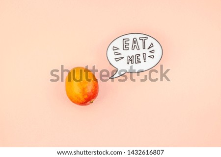 Mango fruit in creative conceptual top view flat lay composition with lightbox bubble with Eat me handwritten slogan isolated on pink background in minimal style with copy space. Pop art poster