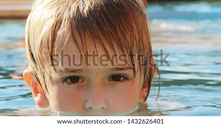 Little child boy looking to camera portrait at the swimming pool water