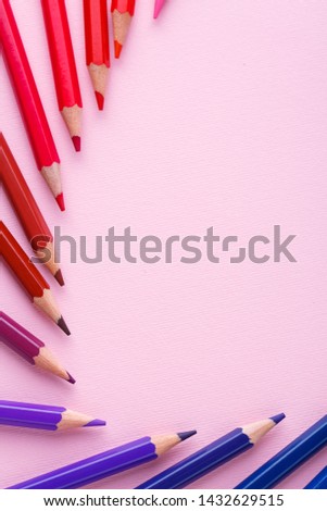 A group of bright wooden pencils on a pink background. Bright color palette of crayons on the table. Top view, flat lay. copyspace