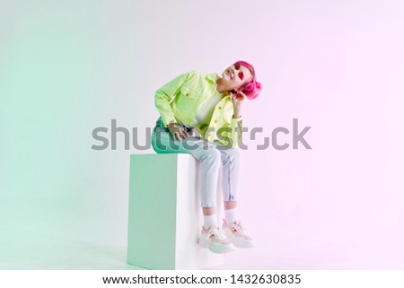 a woman with pink hair sits bowed her head