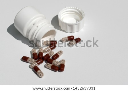 Pills sent from a jar on a white background.