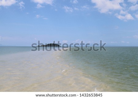 Scenery of attractive golden dragon beach under clear sea water surface in sunny day with small island and cloudy blue sky background. Andaman sea.