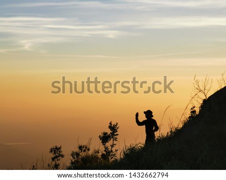Silhouette of a men taking selfie during sunset with flowering grass