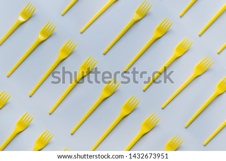 Disposable picnic yellow forks in diagonal on grey. Top view. Flat lay. Pattern.