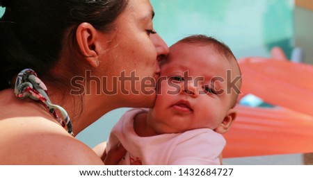Newborn baby being kissed by mom.