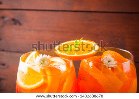 Cocktail aperol spritz on wooden boards. Summer alcoholic cocktail with orange slices and flowers. Aperol spritz on wooden boards