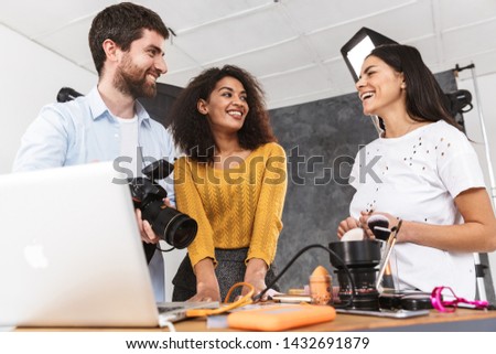 Portrait of creative multiethnic people man and women looking at laptop while photo shooting with professional camera in studio
