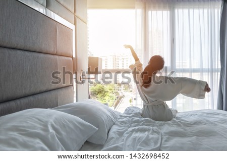 Hotel room comfort with good sleep easy relaxation lifestyle of Asian girl on bed have a nice day morning waking up, taking some rest, lazily relaxing in guest bedroom in city hotel  Royalty-Free Stock Photo #1432698452