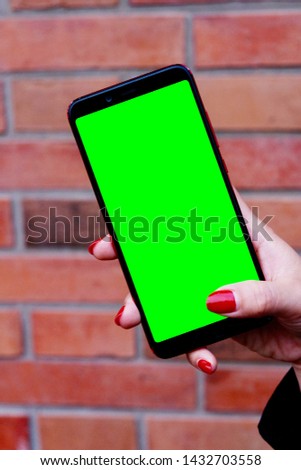 close up business woman hand holding green screen smartphone. Blur red brick wall