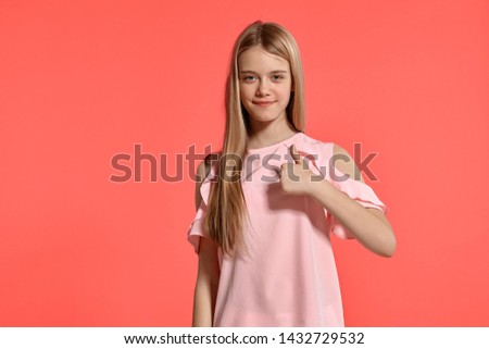 Studio portrait of a beautiful girl blonde teenager in a rosy t-shirt posing on pink background.