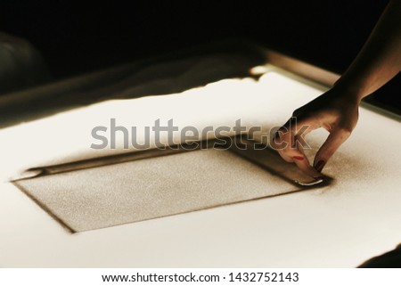 Sand animation at wedding reception. Hand drawing on sand on light box in dark room, creative sand show. Person painting on sand