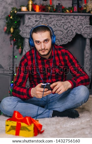 guy on the background of the Christmas fireplace listens to music on your smartphone