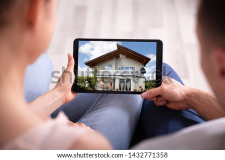 Close-up Of A Couple Looking At New House On Tablet