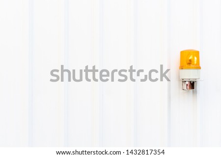 White corrugated metal wall texture with yellow emergency light on the right side