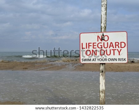No lifeguard on duty. Swim at your own risk. Beach sign. Waves crashing in background. Lake Michigan, Milwaukee, Wisconsin, United States